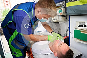 Male paramedic puts a drip on a patient in ambulance