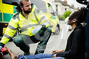 Male paramedic putting on an oxygen mask to an injured woman on a road photo