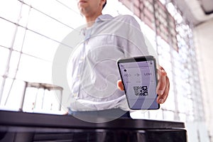 Male Passenger In Airport Departure Lounge Scanning Digital Boarding Pass On Smart Phone