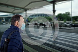 Male passenger in blue face mask get off an airport terminal