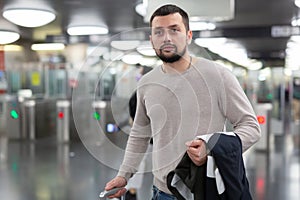 Male passenger in casual clothing near baffle gate in underground platform closeup