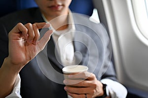 A male passenger holding a cup of water and an airsick motion sickness pills