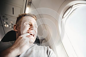 Male passenger in plane screams and cries, aerophobia. background of porthole. Concept fear of flying on airplane