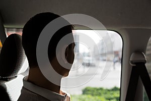 A male passenger rides in a taxi looking out the window.