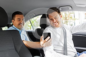 Male passenger showing smartphone to car driver