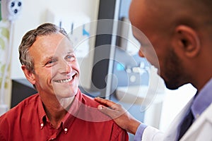 Male Patient Being Reassured By Doctor In Hospital Room