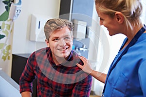 Male Patient Being Reassured By Nurse In Hospital Room