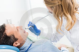 Male patient at dental procedure using dental drill in modern