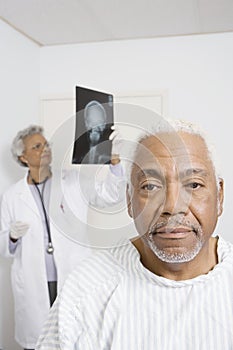 Male Patient With Doctor Examining X-Ray In Background