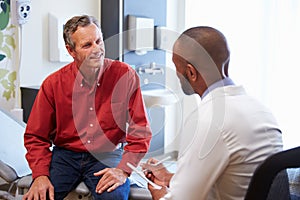 Male Patient And Doctor Have Consultation In Hospital Room