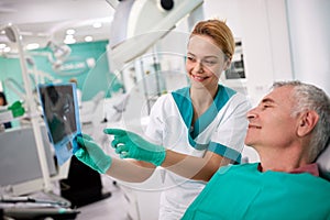 Male patient and female dentist looking at teeth X-ray