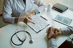 Male patient listening to doctor at desk and consulting with healthcare in hospital