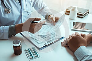 Male patient listening to doctor at desk and consulting with healthcare in hospital