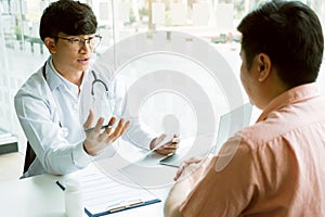 Male patient listening to doctor at desk and consulting with healthcare in hospital