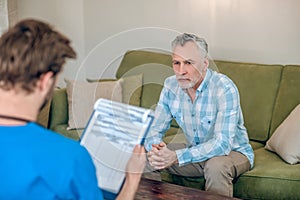 Male patient looking at a physician with a clipboard