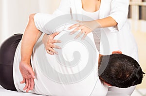 Male patient lying down sideways with female physio therapist performing some stretch excercises