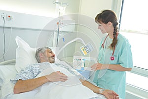 Male patient lying in hospital bed while nurse checking