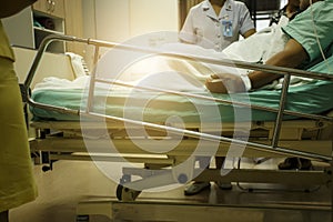 Male patient lying in hospital bed talking with nurse about his