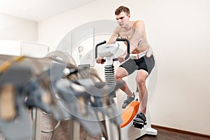 A male patient, pedaling on a bicycle ergometer stress test system for the function of his heart checked. Athlete does a
