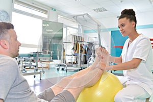 Male patient during physical therapy praxis and female physiotherapist photo