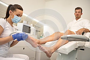 Male patient in the process of hardware pedicure procedure