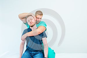 Male patient receiving massage from therapist. A chiropractor stretching his patient`s neck in medical office. Neurological