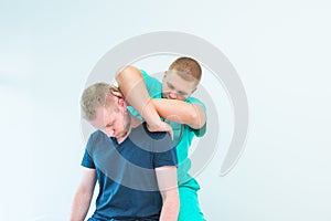 Male patient receiving massage from therapist. A chiropractor stretching his patient`s neck in medical office. Neurological