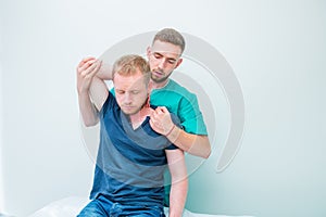 Male patient receiving massage from therapist. A chiropractor stretching his patient`s spine and hands in medical office.
