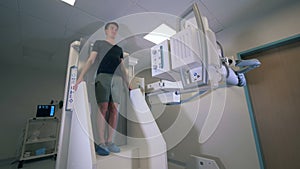 Male patient`s body is getting scanned with x-ray equipment.