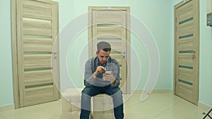 Male patient using phone while waiting for his doctor appointment