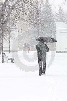 Male pedestrian hiding from the snow under umbrella, vertical