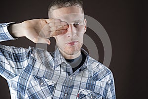 Male person closes his eye with his hand, abstract happy face gesture