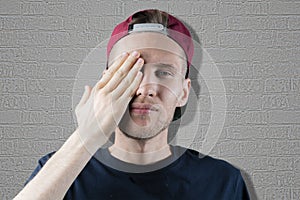 Male person closes his eye with his hand, abstract happy face gesture