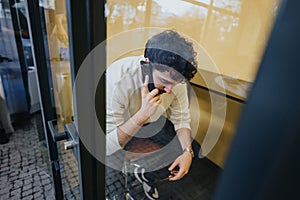 Male person having private phone call in soundproof phone booth at the office.