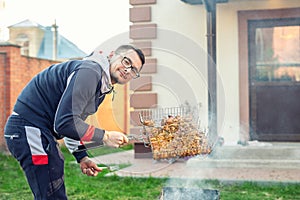 Male person preparing chicken wings on grill at open fire brazier. Barbecue  friens home party at house backyard. Weeken bbq