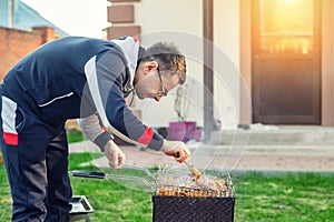 Male person preparing chicken wings on grill at open fire brazier. Barbecue  friens home party at house backyard. Weeken bbq