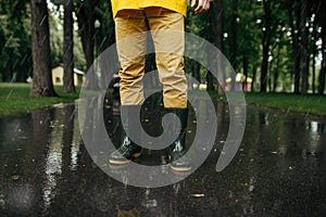 Male person in rain cape and rubber boots