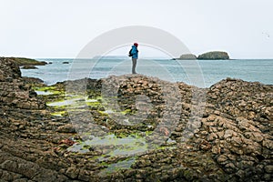 Male person stand on rugged shore enjoy seascape alone outdoors.Game of thrones filming location fishing village in Ballintoy.