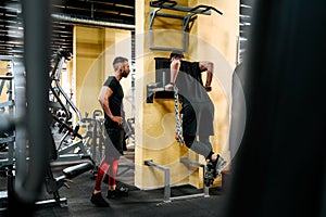 Male personal trainer helping and assisting clients in the gym. Fitness details of healthy life