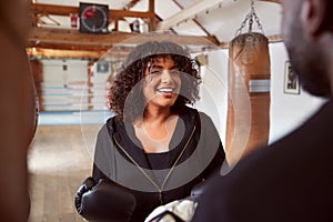 Male Personal Trainer Sparring With Female Boxer In Gym Using Training Gloves