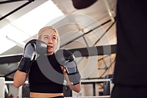 Male Personal Trainer Sparring With Female Boxer In Gym Using Training Gloves