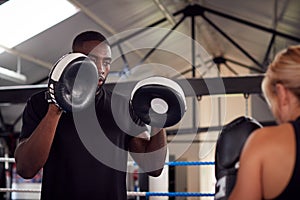 Male Personal Trainer Sparring With Female Boxer In Gym Using Training Gloves