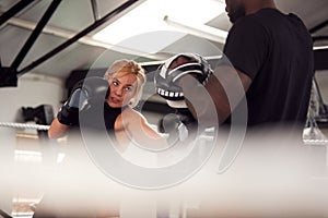 Male Personal Trainer Sparring With Female Boxer In Gym Using Training Gloves