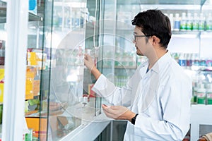 A male pharmacist holding medicine box and capsule pack in pharmacy drugstore