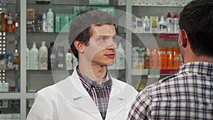 Male pharmacist talking to his client at the drugstore