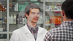 Male pharmacist talking to his client at the drugstore