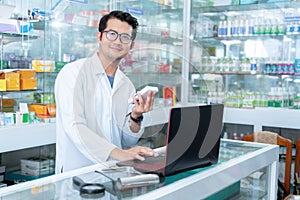 A male pharmacist use a laptop in a drugstore and look at the camera , Medical healthcare concept