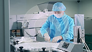 Male pharmacologist is putting plastic tubs onto the conveyor