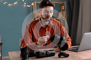 Male photographer ready to insert memory card to his professional DSLR camera while working in home office.