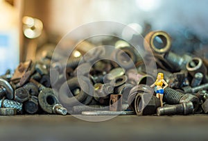 Male photographer standing to take photo a female model on pile of old screws nuts and bolts